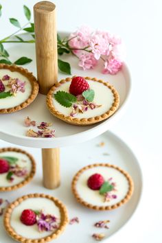 small desserts are displayed on three tiered trays with flowers and greenery