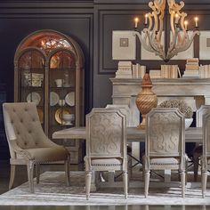 a dining room table with chairs and a chandelier in front of the fireplace