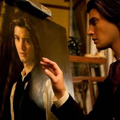 a young man is looking at a portrait of the actor, who appears to be holding something in his hand