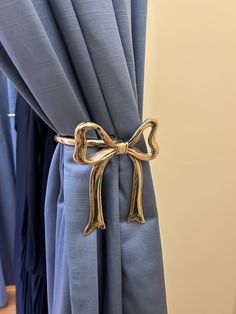 a curtain with a bow tie on it in front of blue drapes and curtains