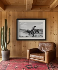 a living room area with a chair, rug and framed photograph on the wooden wall