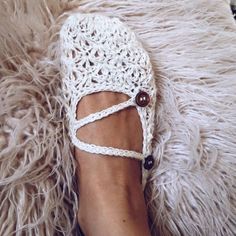 a woman's feet with crocheted shoes on top of a furry rug