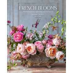 a vase filled with lots of pink flowers on top of a wooden table covered in greenery