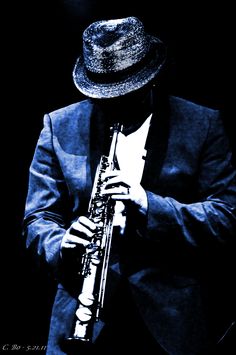 a man in a suit and hat holding a saxophone