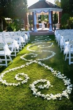 an outdoor ceremony setup with white flowers on the grass and petals in the shape of a heart