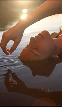 a woman laying on top of a body of water next to the sun shining down