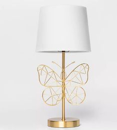 a gold butterfly lamp with a white shade on the base and a white lampshade