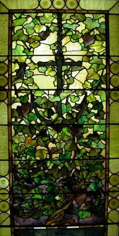 a stained glass window with a cross in the center and green leaves on it's sides