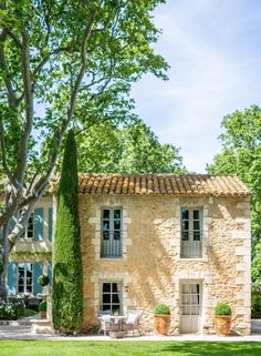 an old stone house is surrounded by greenery and trees in front of the building