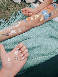 two people with tattoos on their arms are sitting in the grass and one person has her hand painted