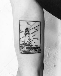 a black and white photo of a lighthouse tattoo on the left inner arm, with clouds in the background