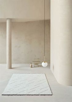 a white rug and chair in a room with two columns on either side of the room