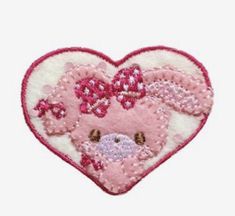 a pink and white heart shaped patch with a teddy bear on it's side