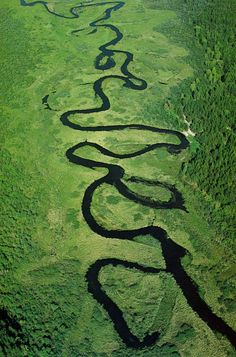 an aerial view of a river running through a lush green field