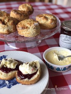 scones with jam and butter on a plate next to a bowl of cream cheese