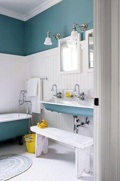 a blue and white bathroom with a tub, sink, mirror and yellow rubber ducky toy