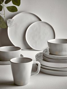 white dishes and cups are stacked on top of each other