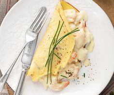 a white plate topped with an omelet covered in shrimp