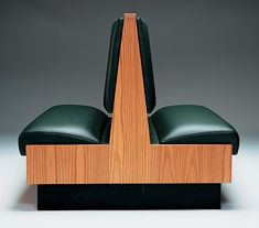 a chair made out of wood and green leather on top of a black base with an arrow in the middle