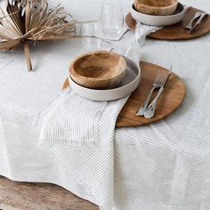 the table is set with two wooden bowls and silverware, along with other place settings