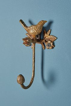 a metal hook with a bird on it's side and two flowers attached to it