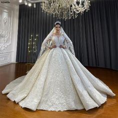 a woman in a white wedding dress standing next to a chandelier