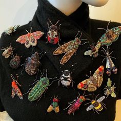 a close up of a person wearing a black sweater with many colorful bugs on it