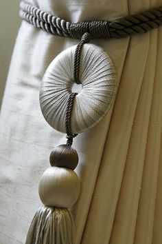 a close up of a white curtain with tassels and beads hanging from it