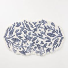 a blue and white rug with leaves on the bottom, in front of a white background