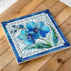 a blue and white tile with flowers on the bottom is sitting on a wooden floor