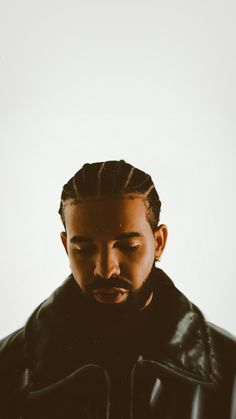 a man with his eyes closed wearing a black leather jacket and standing in front of a white wall