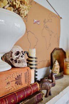 a skull sitting on top of some books next to a white vase and other decorative items