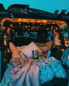 the bed in the back of a truck is covered with blankets and lights