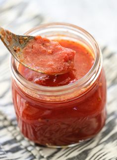 a spoon full of ketchup on top of a jar