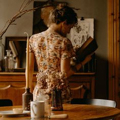 a woman standing in front of a wooden table