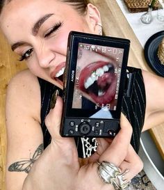 a woman holding up a cell phone to take a photo with her mouth open and tongue out