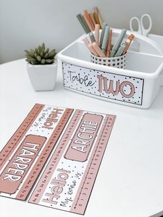 two pink tickets sitting on top of a white table next to a potted plant