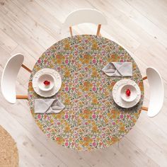 an overhead view of a table with two plates and cups on it, in front of a wooden floor