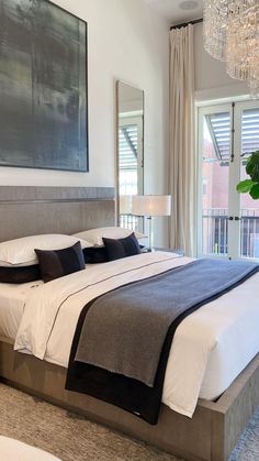 a bedroom with a large bed and chandelier hanging from it's ceiling