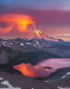 the sun is setting over a mountain with clouds in the sky and water below it