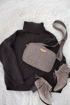 a gray purse and some shoes on a white blanket