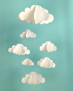 paper clouds hanging from the ceiling in front of a blue wall