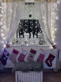 a window with christmas stockings hanging from it's sides and lights on the windowsill