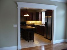 an empty kitchen with wooden floors and dark cabinets