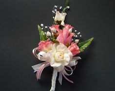 a boutonniere with pink and white flowers on a black background, the bride's corsage