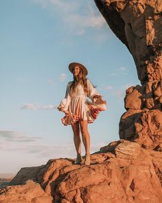 a woman standing on top of a rocky cliff