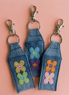 three denim key chains with crocheted flowers on them