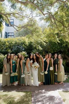 a group of women standing next to each other in front of a lush green tree