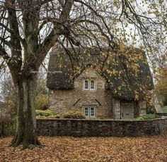 an old stone house surrounded by trees and leaves