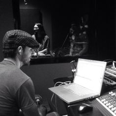 a man sitting in front of a laptop computer on top of a desk next to sound mixing equipment